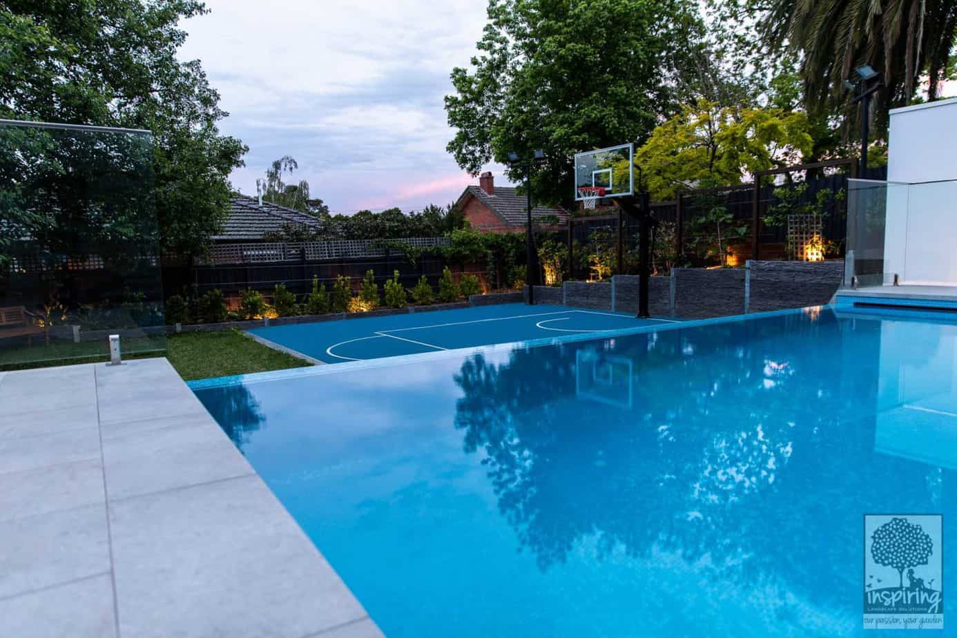 Side view of backyard, basketball court and mini fruit orchard from lap pool in Camberwell garden design