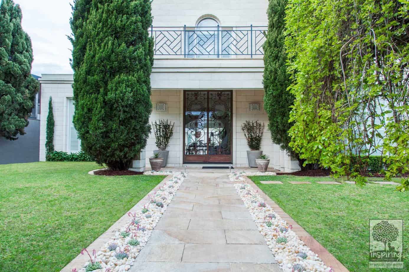 Front view of tall green conifers announcing Brighton garden design front entry