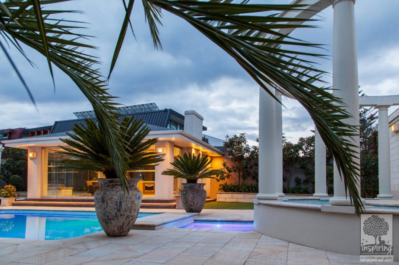 Brighton landscaped pool at night with lights on and styled with pots