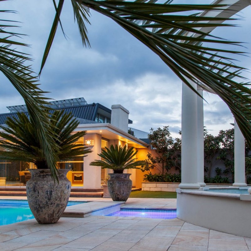 Brighton landscaped pool at night with lights on and styled with pots
