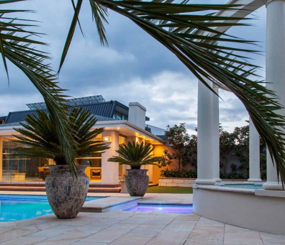 Brighton landscaped pool at night with lights on and styled with pots