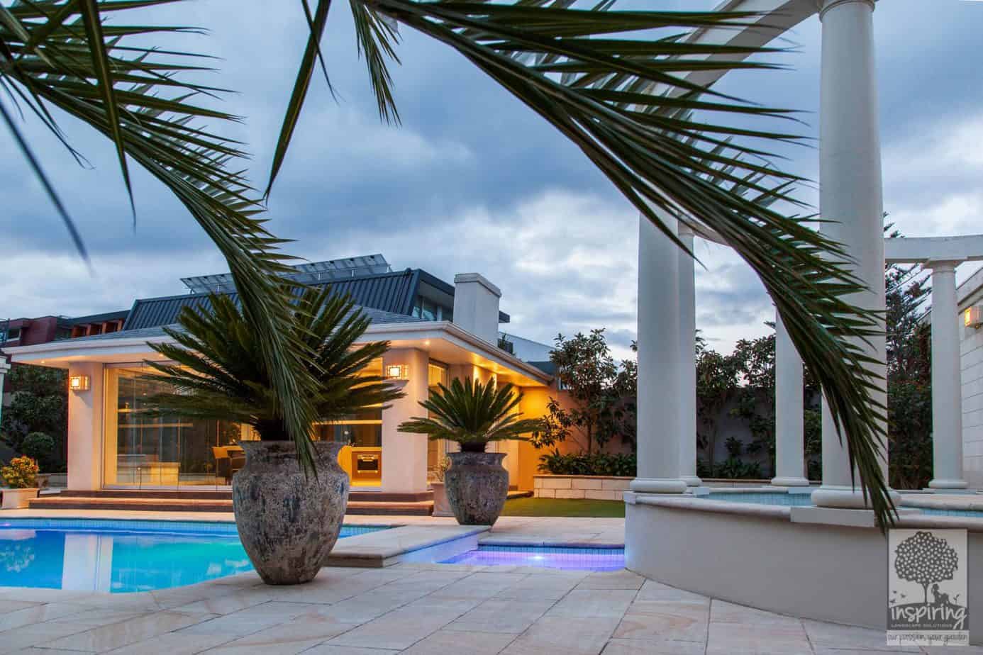 Brighton landscaped pool at night with lights on and styled with pots