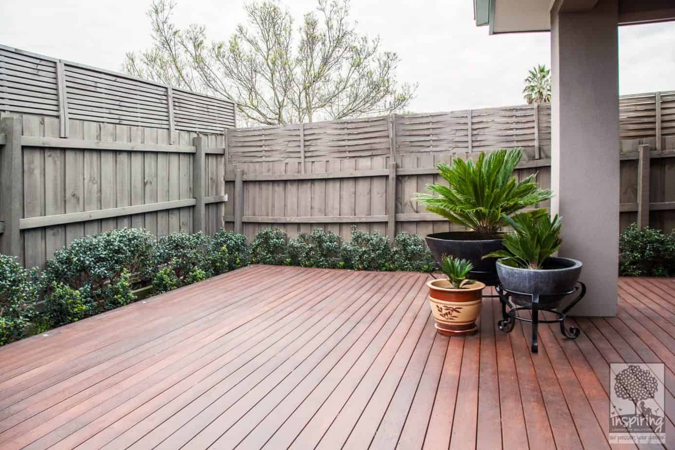 Backyard merbau decking in Ashburton garden design with flowering hedges