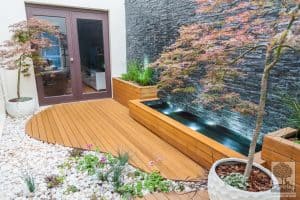 Custom deck shaped like a river bed joining a wall to wall cascading water feature in Maribyrnong landscape design