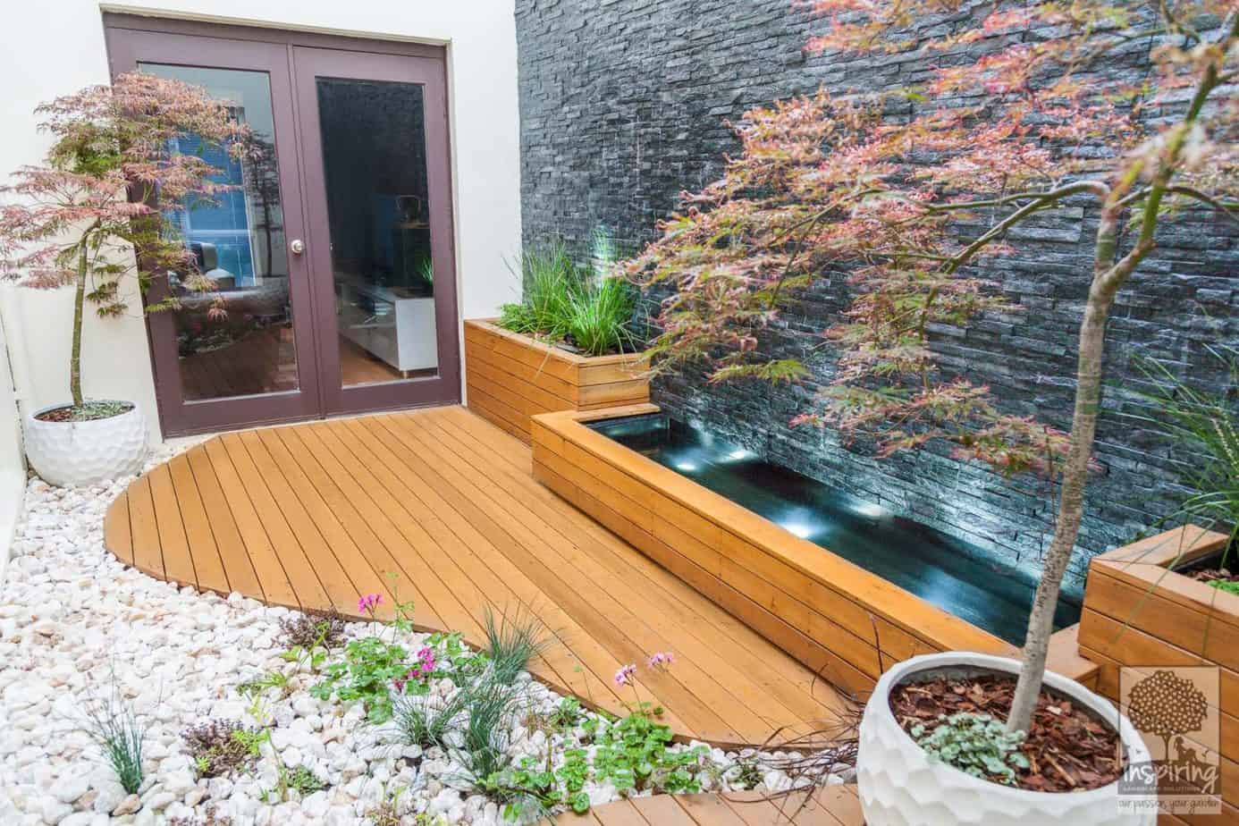 Custom deck shaped like a river bed joining a wall to wall cascading water feature in Maribyrnong landscape design