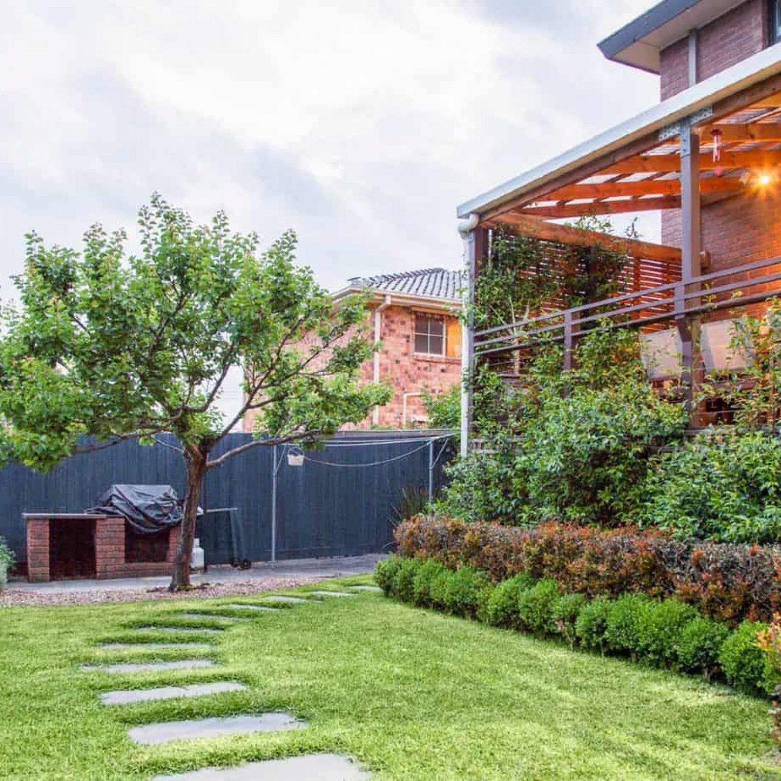 View of backyard grassed area, deck and vegetable patch in Vermont South garden design by Parveen Dhaliwa