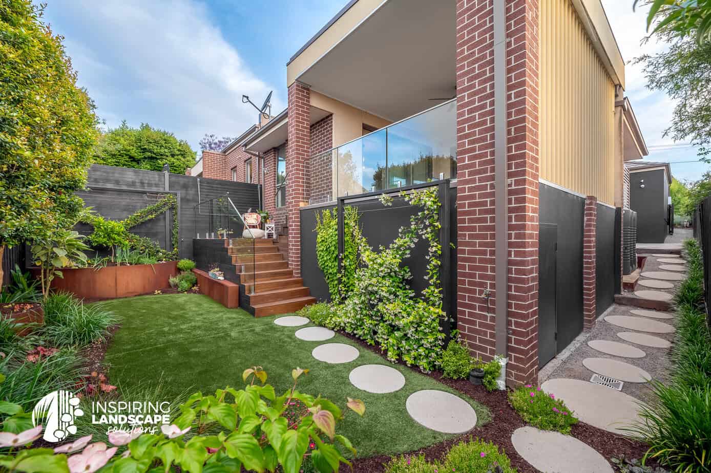 Rear garden complete with a timber staircase, upstairs patio and pathway with different sized circular pavers in Mount Waverley garden design